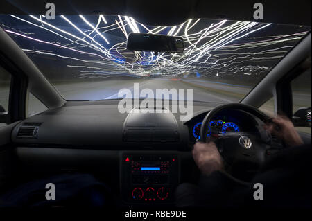 Il traffico notturno di percorsi in autostrada con i fari anteriori e i sentieri di luce sulla M25 svincolo Foto Stock