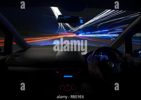 Il traffico notturno di percorsi in autostrada con i fari anteriori e i sentieri di luce sulla M25 slip nodo stradale Foto Stock