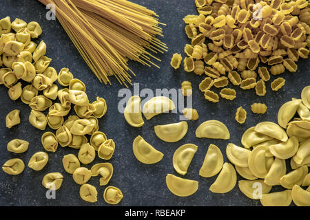 Varie e tradizionali piatti di pasta italiana sulla pietra scuro dello sfondo. Foto Stock