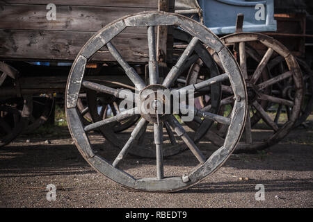 Ruota in legno del carro vintage permanente sulla strada rurale Foto Stock