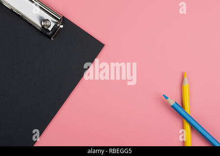 Graffa nera scheda e matita colorata su sfondo rosso Foto Stock