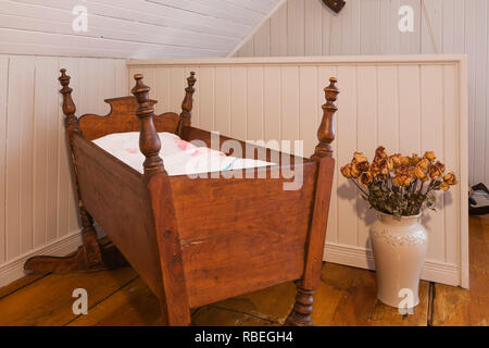 In legno antico presepe basculante in un angolo della camera da letto principale sul pavimento del piano superiore all'interno di un vecchio 1862 cottage in stile home Foto Stock