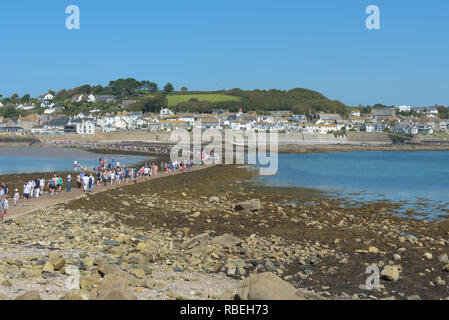 Coda di persone che attraversano la striscia di terra tra Marazion e St Michael's Mount durante la bassa marea. Cornovaglia, Inghilterra. Foto Stock