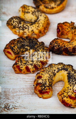 Biscotti fatti in casa con i semi di papavero e marmellata su un tavolo di legno. Deliziosi dessert. Foto Stock