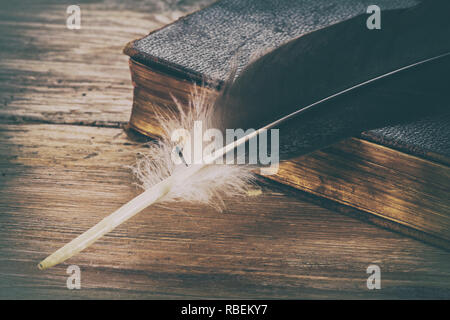 Vecchio libro e piuma penna sul legno retrò sfondo tabella Foto Stock