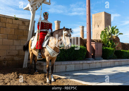 Rabat, Marocco - 29 Novembre 2018: una guardia sorge sul suo cavallo davanti la torre Hassan o Tour Hassan che è il minareto di una moschea incompleto ho Foto Stock