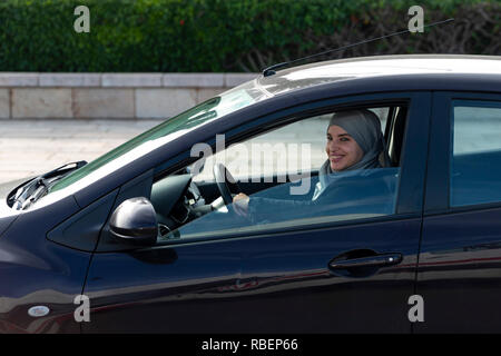 Rabat, Marocco - 29 Novembre 2018: donna marocchina con hidjab aziona un auto vicino alla Torre Hassan e il Mausoleo di Mohammed V. Foto Stock