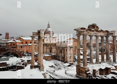 Inverno a Roma. Vista di congelati Forum Romano antiche rovine e chiesa barocca con neve Foto Stock
