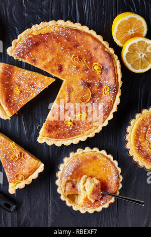 Pasqua svizzera dessert - torte di riso spolverati con zucchero a velo e la scorza di limone tagliata a fettine, gateau de Paques, Osterfladen, su una tavola nera con lem Foto Stock