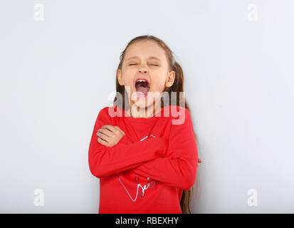 Kid ragazza urlando forte con la bocca aperta e bracci ripiegati su sfondo blu con vuoto lo spazio di copia Foto Stock