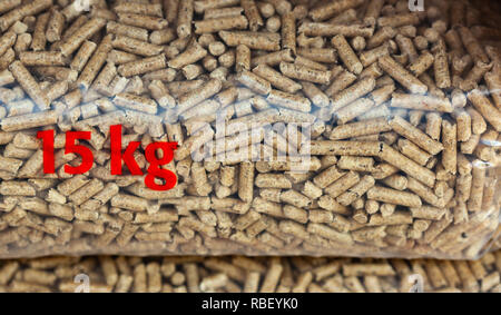 Pila di sacchi di plastica di quindici chilogrammi pieno con pellet di legno. Foto Stock