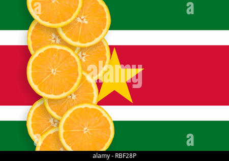 Suriname bandiera e la fila verticale di orange agrumi fette. Concetto di crescita nonché di importazione ed esportazione di agrumi Foto Stock