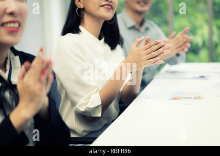Plaudendo all'altoparlante. Gruppo di felice la gente di affari in convenzionale seduti a sedie in sala riunioni e applaudire. Foto Stock