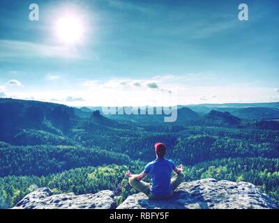 Uomo tranquillo le pratiche yoga in cima alla montagna, Sun è in aumento nella parte anteriore Foto Stock