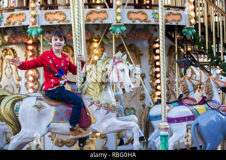 Sweet boys, fratelli, in sella a un Babbo Natale sulla slitta a merry-go-round, giostra attrazione in Europa, bambini attivi, inverno Foto Stock