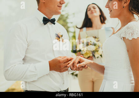 Spose, dove lo sposo indossa un anello su una sposa del dito. Focus sulle mani Foto Stock