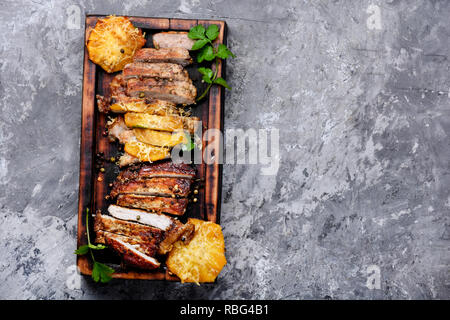 Tagliate a fette grigliate di carne arrosto con ananas sul tagliere in legno.Vista Superiore Foto Stock