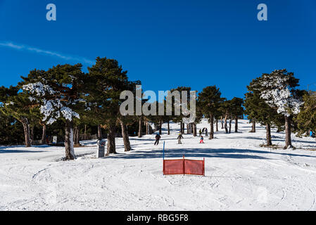 Navacerrada, Spagna - 7 Dicembre 2017: sciatori sci in discesa nella stazione sciistica di Guadarrama mountain range in inverno una giornata soleggiata con cielo blu Foto Stock