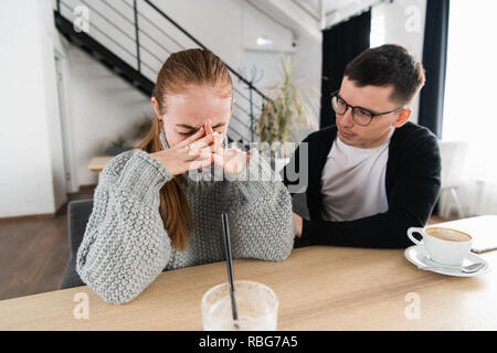 Riunione di una donna triste e un amico o un ragazzo cerca conforto per lei nel cafe Foto Stock