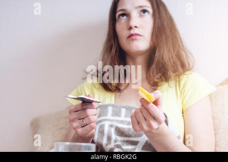 Donna con un freddo sceglie tra pillole e vitamine per il trattamento. L'influenza stagionale in inverno Foto Stock