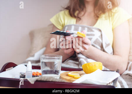 Donna con un freddo sceglie tra pillole e vitamine per il trattamento. L'influenza stagionale in inverno Foto Stock