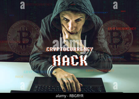 Un pirata informatico con una faccia sta cercando di rubare cryptocurrency utilizzando un computer. Truffa a Cryptojacking Foto Stock