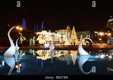 Notte Baku nel nuovo anno con una rutilante albero di Natale decorato con motivi e una fontana del cigno in primo piano. Azerbaigian Foto Stock