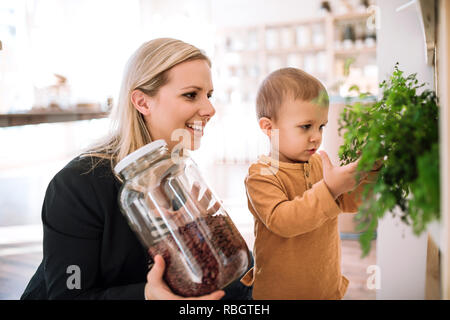 Una giovane donna con un bimbo piccolo ragazzo acquisto di generi alimentari in rifiuti zero shop. Foto Stock