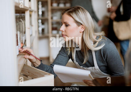 Una femmina di shop assistant funziona in uno zero-rifiuti shop. Foto Stock