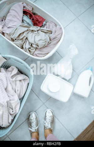 Panni sporchi in cesti con detergenti sul pavimento, vista da sopra Foto Stock