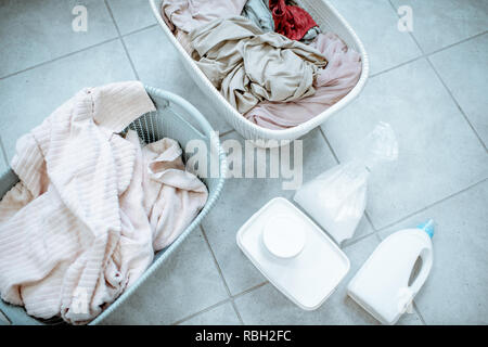 Panni sporchi in cesti con detergenti sul pavimento, vista da sopra Foto Stock