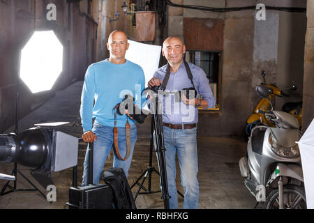 Ritratto di due fotografi di successo con le loro macchine fotografiche professionali durante le riprese fotografiche su town street Foto Stock