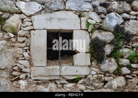 Vecchia finestra con barre in una vecchia casa rovina di pietra nel vecchio villaggio (Piskopiano) sull isola di Creta in Grecia. Foto Stock
