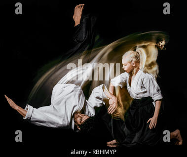 Due Combattenti budokas l uomo e la donna pratica di Aikido studio shot isolato su sfondo nero Foto Stock