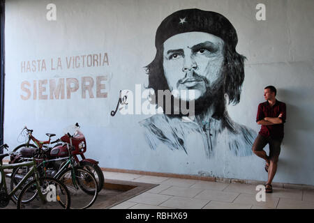 SANTA CLARA, CUBA - febbraio 22: Turistico sorge accanto alla parete murale con la propaganda della rivoluzione il 22 febbraio 2011 in Sancti Spiritus, Cuba. Revolutio Foto Stock