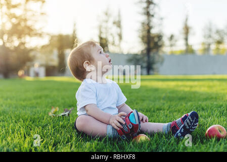 Carino il bambino gioca con le mele su un prato verde nel Parco. Il concetto di uno-anno-vecchio figlio Foto Stock