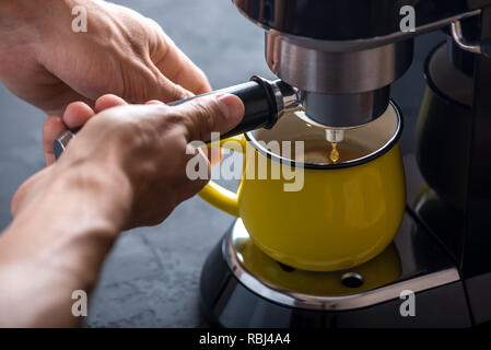 Preparazione di un espresso. Nero caffè versando dalla macchina nella coppa. Professional per l'infusione di caffè a casa Foto Stock