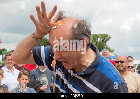 Partecipante a giocare alla roulette russa con le uova al mondo uovo gettando campionati, Swaton Village Fair, Lincolnshire, Regno Unito Foto Stock