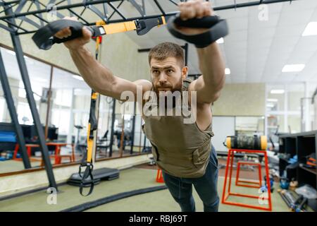 Sport militare, muscolare caucasian barbuto uomo adulto facendo esercizi in palestra vestita di corazzate antiproiettile vest. Foto Stock