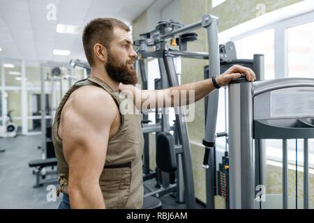 Ritratto caucasico muscolare barbuto uomo adulto in palestra, vestito in corazzate antiproiettile vest, militare sport. Foto Stock