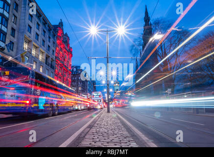 Notte sentieri di autobus e tram, Princes Street, con orologio Balmoral e Monumento Scott, Edimburgo, Scozia, Regno Unito Foto Stock