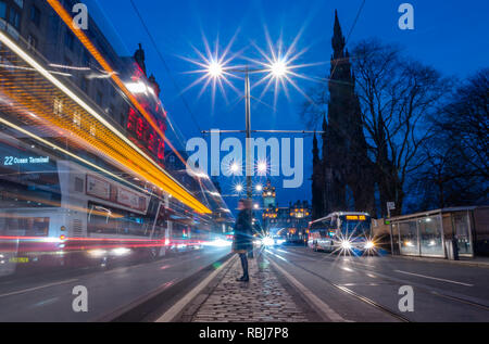 Notte sentieri di autobus e tram, Princes Street, con orologio Balmoral e Monumento Scott, Edimburgo, Scozia, Regno Unito Foto Stock