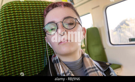 Giovane donna in appoggio ai suoi occhi e equitazione sulla DART e i mezzi di trasporto pubblici, a Dublino, Irlanda. Foto Stock