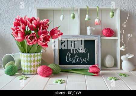 Primavera sfondo con decorazioni di Pasqua, tulipani e una scheda di gesso. Testo 'Frohe Ostern' sulla lavagna significa 'Felice Pasqua" in tedesco. Foto Stock