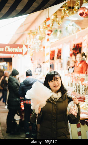 Strasburgo, Francia - Dic 23, 2017: cinese felice giovane donna tenendo un grande caramella di cotone a piedi tra le righe del Mercatino di Natale a Strasburgo Alsazia Foto Stock