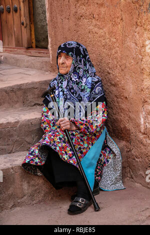 ABYANEH, IRAN- Settembre 23, 2018:una donna iraniana si siede sui gradini della sua casa nel villaggio di montagna di Abyaneh con caratteristico colore rosso case. Ho Foto Stock