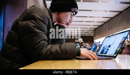 Strasburgo, Francia - 11 GEN 2018: curioso centro-est dell etnia giovane ragazzo utilizzando i più recenti MacBook Pro con retina toccare Bar computer laptop Foto Stock