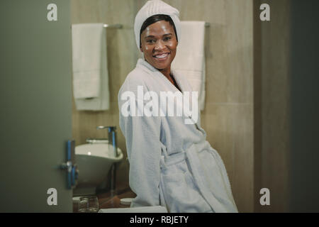 Ritratto di coppia donna africana in piedi in bagno con una pelle risplendente. Femmina in accappatoio appoggiata al lavandino del bagno e guardando la telecamera sorridendo. Foto Stock