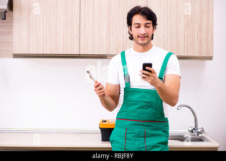 Giovani plumber riparazione toccate in cucina Foto Stock