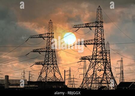 National Grid tralicci di energia elettrica in corrispondenza di Dungeness Kent contro un tramonto spettacolare, England Regno Unito Foto Stock